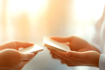Hands exchanging business cards softly.