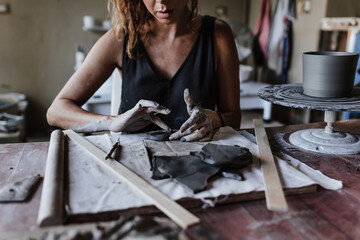 hands of latin woman potter, creating a clay pot on a pottery wheel in her workshop in Mexico Latin America, hispanic female	