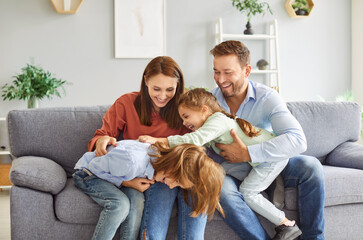 Parents and kids laughing and playing together at home, tickling each other and enjoying leisure...