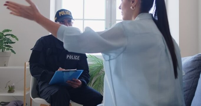 Police officer or detective investigates a crime scene at a home by taking testimony from a victim. The process focuses on collecting evidence and conducting a thorough investigation.