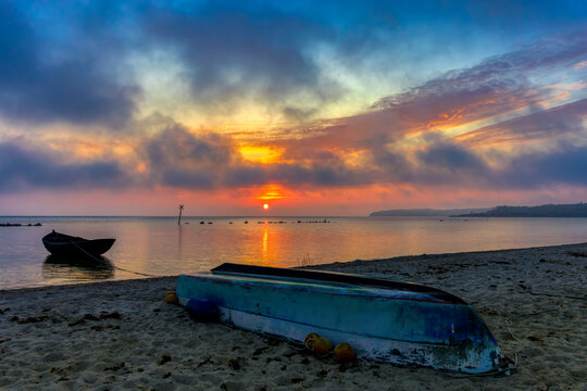 Fishing boats on the beach of a small bay with sunset and drama