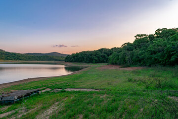 Beautiful view of the V&aacute;rzea das Flores lake, with water lapping the shore, cloudy sky and woods in the background.