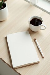 A Blank Notebook Ready for Inspiration Beside a Cup of Coffee and a Pen on a Light Wooden Desk