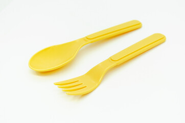 Yellow plastic picnic spoon and fork on white background, copy space