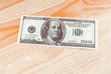One hundred dollars banknote on wooden background, top view