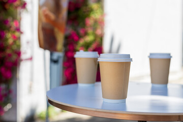 Three cups of coffee sit on a table in front of a sign