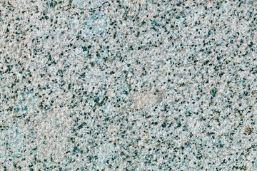 A grey and white stone wall with a few green specks