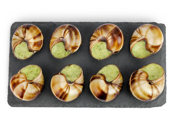 escargot snail filled with garlic and parsley butter on a stone board isolated on white background. Top view. Flat lay