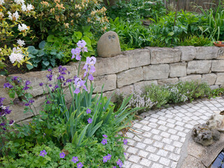 Trockenmauer mit Weg und Pflanzen im Garten 