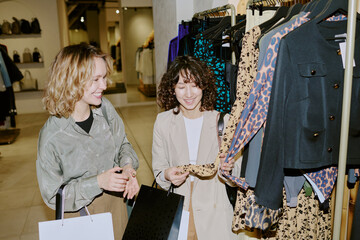 High angle shot of siblings looking over dresses hung on plastic hangers, they smiling and enjoying...