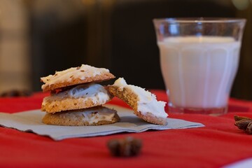 Stack of maple anise cookies, one with a bite out of it and a glass of milk.