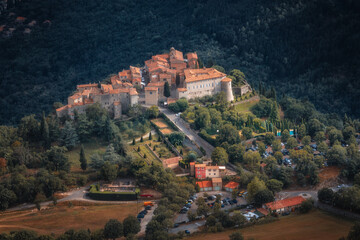 Obraz premium A breathtaking aerial photograph of a medieval village nestled in lush greenery, featuring historic stone buildings, terracotta rooftops, and elegant gardens. Perfect for promoting travel, cultural he