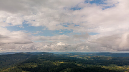 Majestic Mountains, Lush Green Forests, And Soft White Clouds On A Sunny Day. Aerial View Showcasing The Stunning Beauty Of Nature From A High Perspective.	
