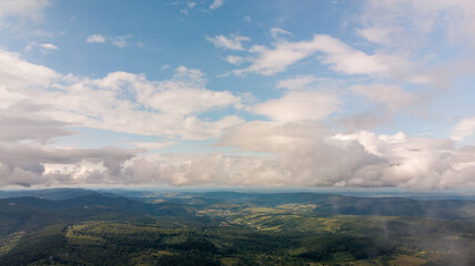 Majestic Mountains, Lush Green Forests, And Soft White Clouds On A Sunny Day. Aerial View Showcasing The Stunning Beauty Of Nature From A High Perspective.	
