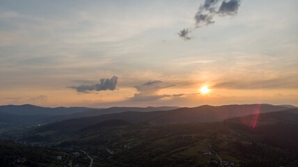 Aerial View Of A Small Town Nestled Among Majestic Mountains And Expansive Agricultural Fields At Sunset, Showcasing The Serene Beauty Of The Rural Landscape.