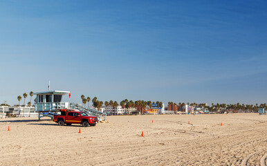 Fototapeta premium Classic lifeguard tower paired with a rescue vehicle parked nearby on a sandy beach