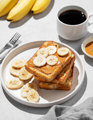 Peanut butter toast  with banana on a plate  on a light background with a cup of espresso coffee