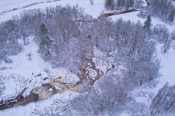 Aerial view of Kuhakoski rapids on a cold winter day with snow covered ground and tree branches, Nurmijärvi, Finland.