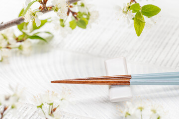 Table adorned with cherry blossom branch and chopsticks, epitomizing Japanese food culture