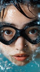 Asian female diver emerges from water showcasing skill and confidence with goggles on in a vivid underwater moment