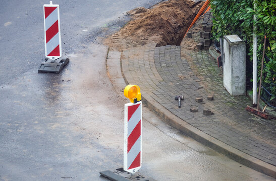 Konzept Glasfaserausbau, Internet, Kommunikation und: Arbeiter bei Bauma&szlig;nahmen f&uuml;r die Verlegung von Glasfaserleitungen f&uuml;r den Hausanschluss in einer Stra&szlig;e