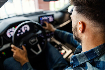 Rear view of a young man typing on gps device in his car.
