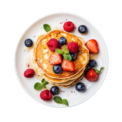 A stack of golden pancakes is adorned with fresh strawberries, raspberries, blueberries and mint leaves on a white plate.