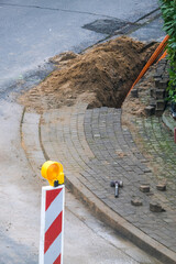 Konzept Glasfaserausbau, Internet, Kommunikation und: Arbeiter bei Baumaßnahmen für die Verlegung von Glasfaserleitungen für den Hausanschluss in einer Straße