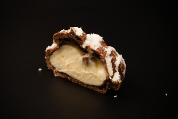 Profiteroles with coconut cream on a black background.