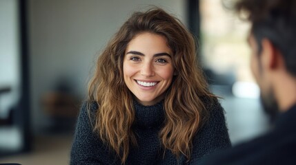 Fototapeta premium Woman with curly hair smiles warmly while conversing in a stylish indoor setting