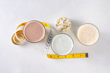 Assortment of different flavors of protein cocktails, with protein powder scoop, measuring tape. Protein shakes for weight loss, set every day protein goals, sport and fitness, healthy lifestyle