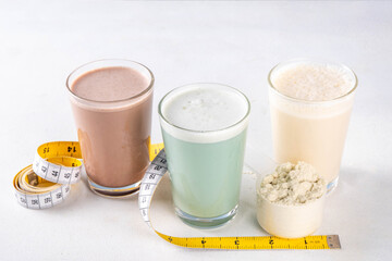 Assortment of different flavors of protein cocktails, with protein powder scoop, measuring tape. Protein shakes for weight loss, set every day protein goals, sport and fitness, healthy lifestyle