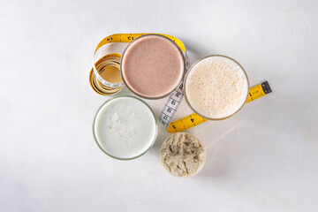 Assortment of different flavors of protein cocktails, with protein powder scoop, measuring tape. Protein shakes for weight loss, set every day protein goals, sport and fitness, healthy lifestyle