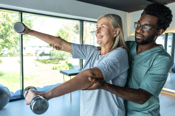 Medic man providing rehabilitation treatment and consulting patients for recovery using dumbbells