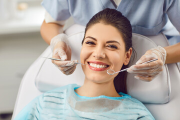 Portrait of a smiling patient with dentist doctor is checking teeth with a dental instrument....