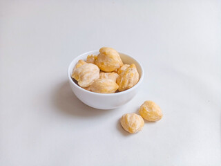 Close up of candlenut or kemiri on the bowl. Isolated on white background