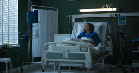 Elderly woman in hospital room, chatting on phone via video call, bringing smiles.