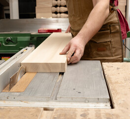 A carpenter saws a board on a machine
