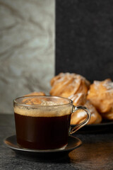 Black coffee in glass cup and cream cakes.
