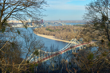 Scenic Autumn View of the Dnieper River in Kyiv, Ukraine – Peaceful Panoramic Cityscape with Pedestrian Bridge, Autumn Trees, Nature, and Tranquil Urban Landscape