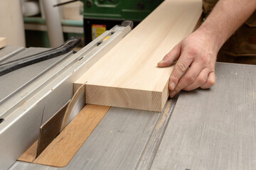 A carpenter saws a thin plank from an ash board