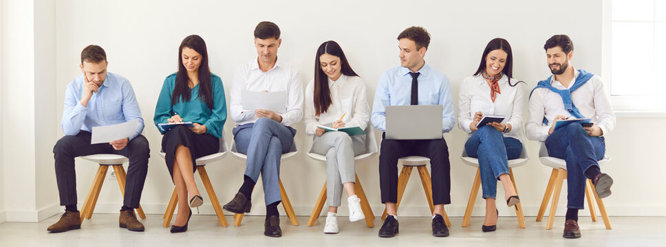 Young business people sitting on chairs in a row with resumes and laptops preparing for meeting or conference. Job candidates seekers waiting for interview invitation turn. Banner.