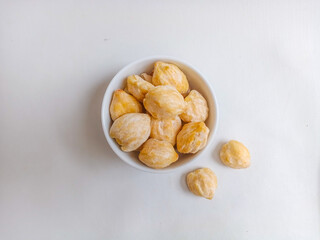 Close up of candlenut or kemiri on the bowl. Isolated on white background