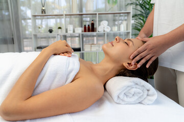 Fototapeta premium Caucasian woman enjoying relaxing anti-stress head massage and pampering facial beauty skin recreation leisure in dayspa modern light ambient at luxury resort or hotel spa salon. Quiescent