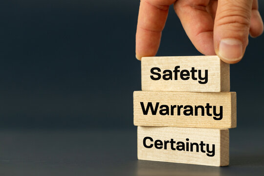 Safety Warranty Certainty Concept words. Business slogan. Building customer safety and trust. Safety, warranty and certainty icons on wooden blocks arranged by businessman's hand. copy space