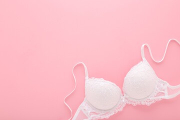 New white lace bra on light pink table background. Pastel color. Female casual underwear. Closeup....