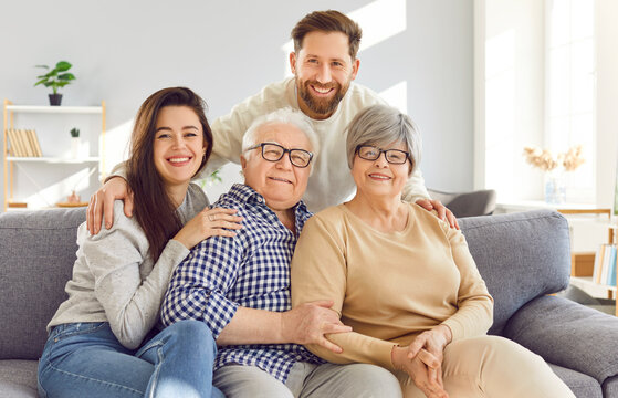 Portrait of a happy family at home, elderly parents or old grandparents, an adult son, and a daughter, smiling and embracing at home. Love and togetherness between grandparents and children.
