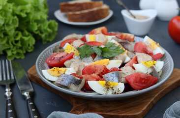 Salad with herring, beetroot, tomato and egg on gray plate