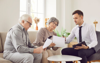 Gray-haired senior couple talking with financial agent about health insurance in retirement sitting...