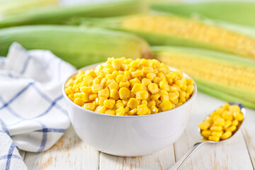 Canned sweet young corn grain in the bowl on a white table, selective focus.
